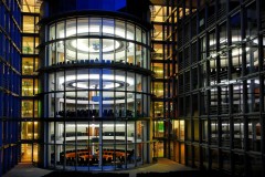 A series of lighted conference rooms in a glass building